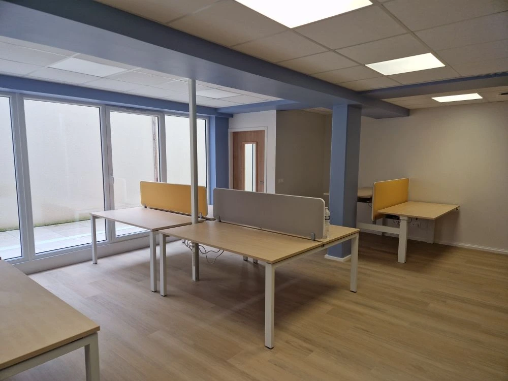 Open space livré avec bureaux bench près des fenêtres — CAF Caen