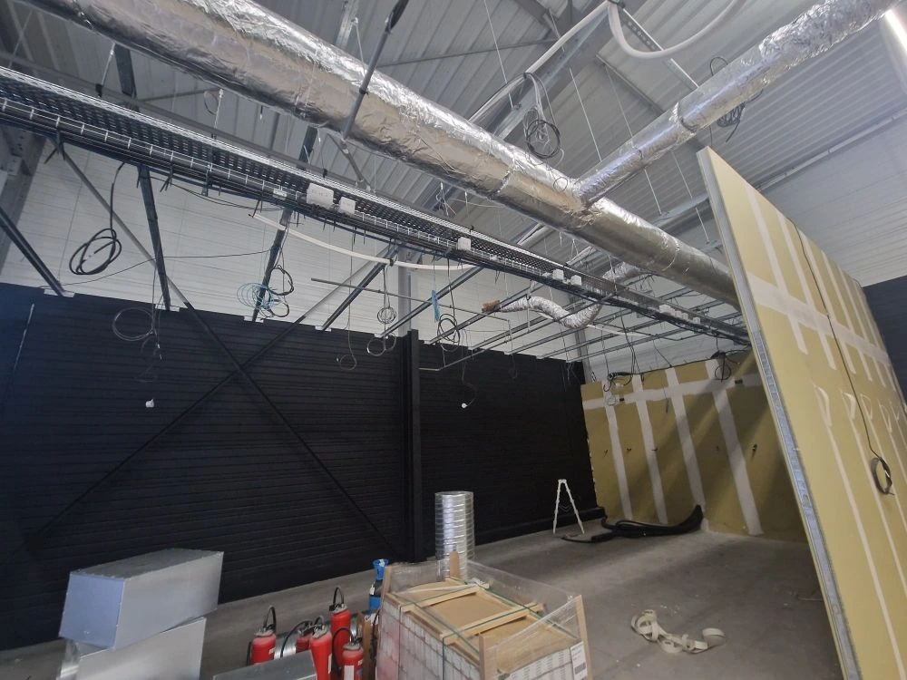 Chemin de câbles dans une zone immersive aux murs noirs — salle EVA Brest