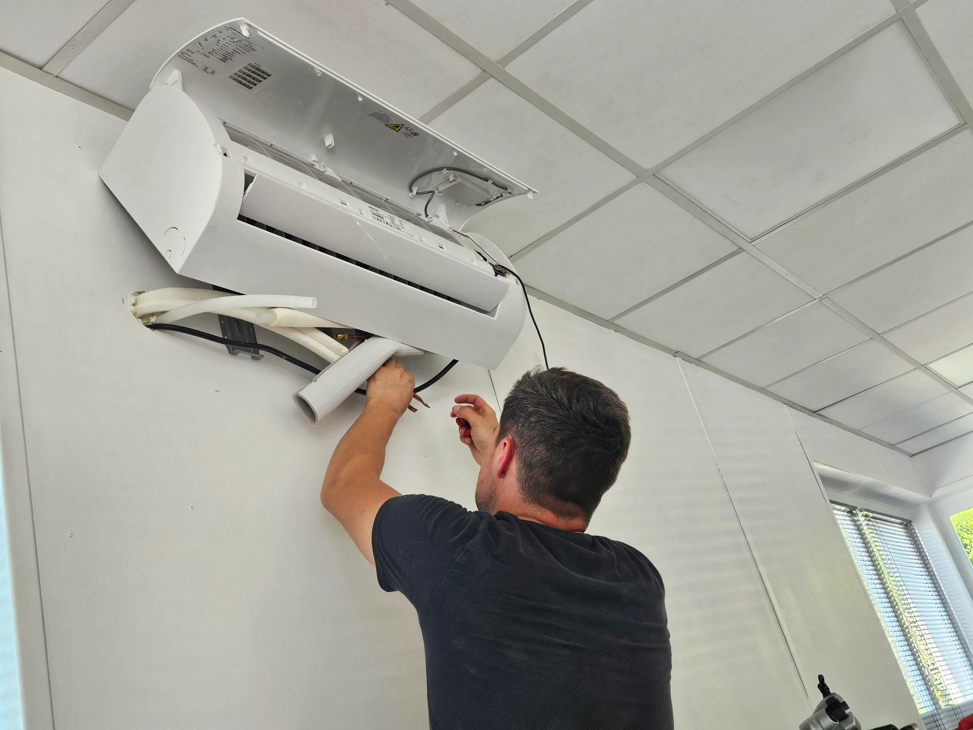Technicien Voltec IP en cours de raccordement de l'unité intérieure de climatisation